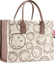 Cremefarbene Shopper-Tasche aus Teddyplüsch mit braunen Smiley-Mustern und zwei braunen Tragehenkeln, frontale Ansicht vor weißem Hintergrund