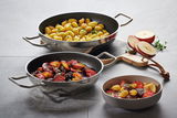 Zwei Schmorpfannen Industar 24cm mit Griffen, gefüllt mit gebratenen Gnocchi und Gemüse, aus der Vogelperspektive fotografiert.