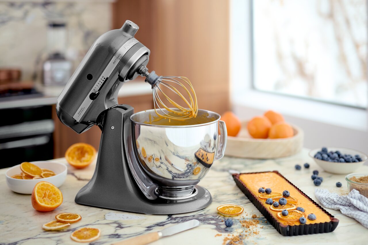 Zilverkleurige keukenmachine met garde in een moderne keuken, zijaanzicht