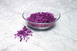 Eine Glasschüssel mit frisch geriebenem Rotkohl auf einer Marmoroberfläche, fotografiert aus der Vogelperspektive.