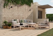 Modernes Lounge-Set auf einer Terrasse mit Blick von vorne, bestehend aus einem Ecksofa und einem Sessel, umgeben von Pflanzen und dekorativen Kissen.
