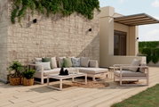 Modernes Lounge-Set auf einer Terrasse mit Blick von vorne, bestehend aus einem Ecksofa und einem Sessel, umgeben von Pflanzen und dekorativen Kissen.