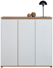 Frontansicht eines XL-Schuhschranks mit drei weißen Türen, einer Holzplatte oben, dekoriert mit zwei Vasen und einer schwarzen Lampe.