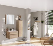 Moderner Badezimmer-Mittelschrank in Holzoptik, rechts an der Wand montiert, mit dekorativen Elementen auf der Oberseite, seitliche Perspektive.