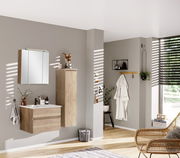 Moderner Badezimmer-Mittelschrank in Holzoptik, rechts an der Wand montiert, mit dekorativen Elementen auf der Oberseite, seitliche Perspektive.