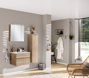 Moderner Badezimmer-Mittelschrank in Holzoptik, rechts an der Wand montiert, mit dekorativen Elementen auf der Oberseite, seitliche Perspektive.
