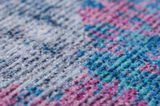 Nahaufnahme eines bunten Teppichs mit einem Muster in Blau-, Rosa- und Grautönen, aus seitlicher Perspektive.