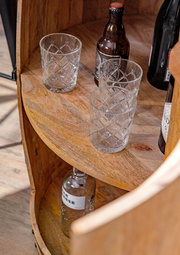 Nahaufnahme eines Bar-Fasses aus Holz mit Gläsern und Flaschen, von oben betrachtet.