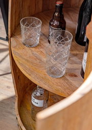 Nahaufnahme eines Bar-Fasses aus Holz mit Gläsern und Flaschen, von oben betrachtet.