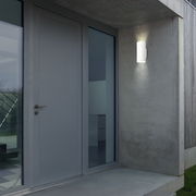 Moderne Akku-Außenwandleuchte an einer Betonwand neben einer Haustür, seitliche Perspektive