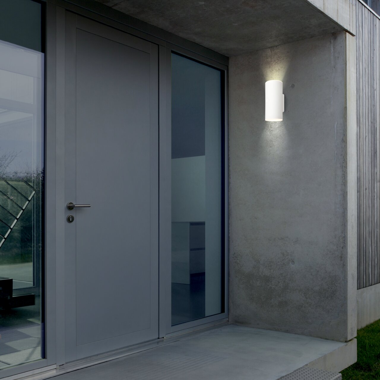 Moderne Akku-Außenwandleuchte an einer Betonwand neben einer Haustür, seitliche Perspektive