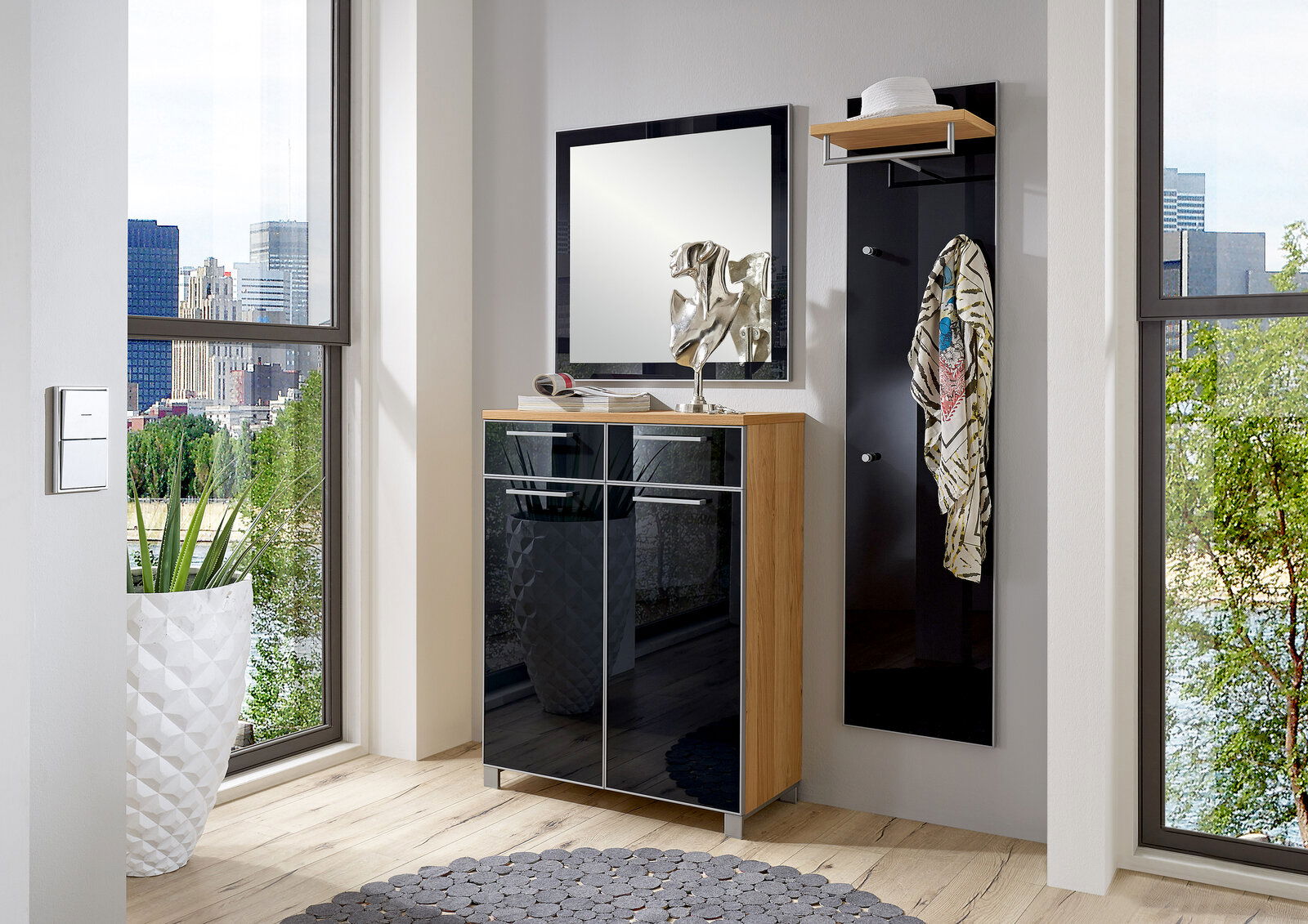 Moderner Eingangsbereich mit einem schwarzen Garderobenpaneel und einem Spiegel, daneben ein eleganter Schuhschrank mit Holz- und Glaselementen. Perspektive von vorne.