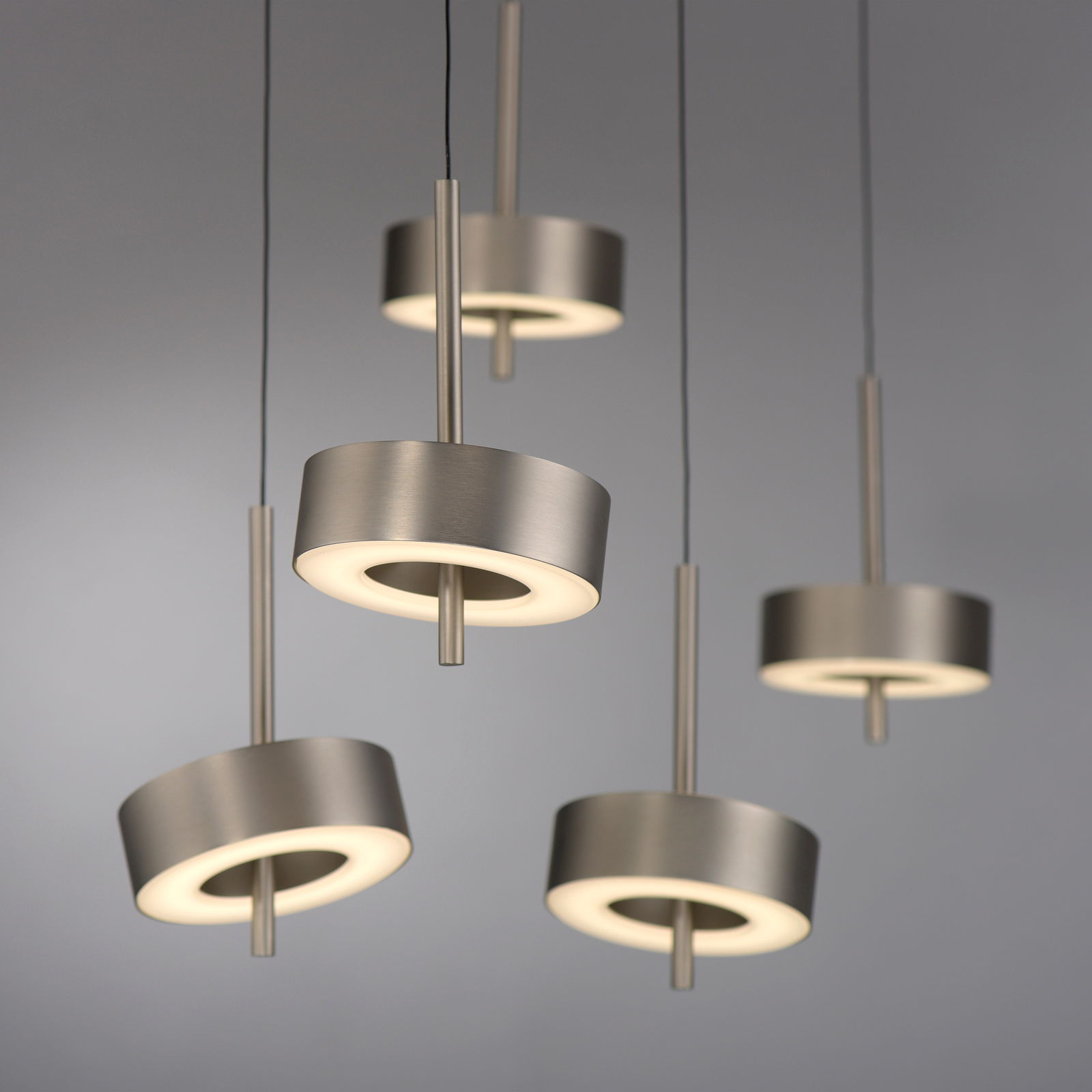 Moderne Pendelleuchte Q-ROTATE in gebürstetem Metall, von unten betrachtet, mit fünf leuchtenden Ringen.