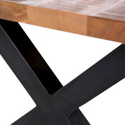 Nahaufnahme eines Esstisches mit einer robusten Holzplatte und einem schwarzen Metallgestell in X-Form, seitliche Perspektive.