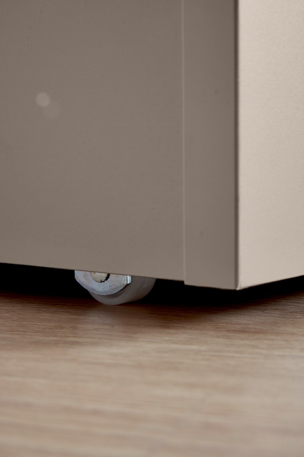 Close-up van een bedkist met wieltjes op een houten vloer, zijaanzicht