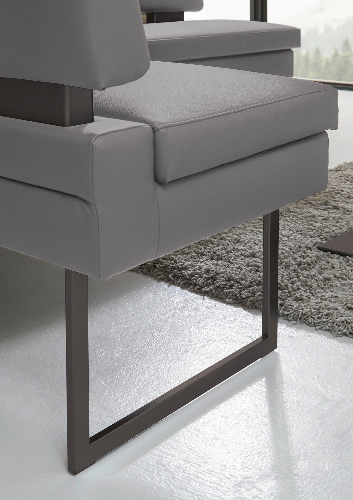 Nahaufnahme einer modernen grauen Eckbank mit Metallgestell, seitliche Perspektive