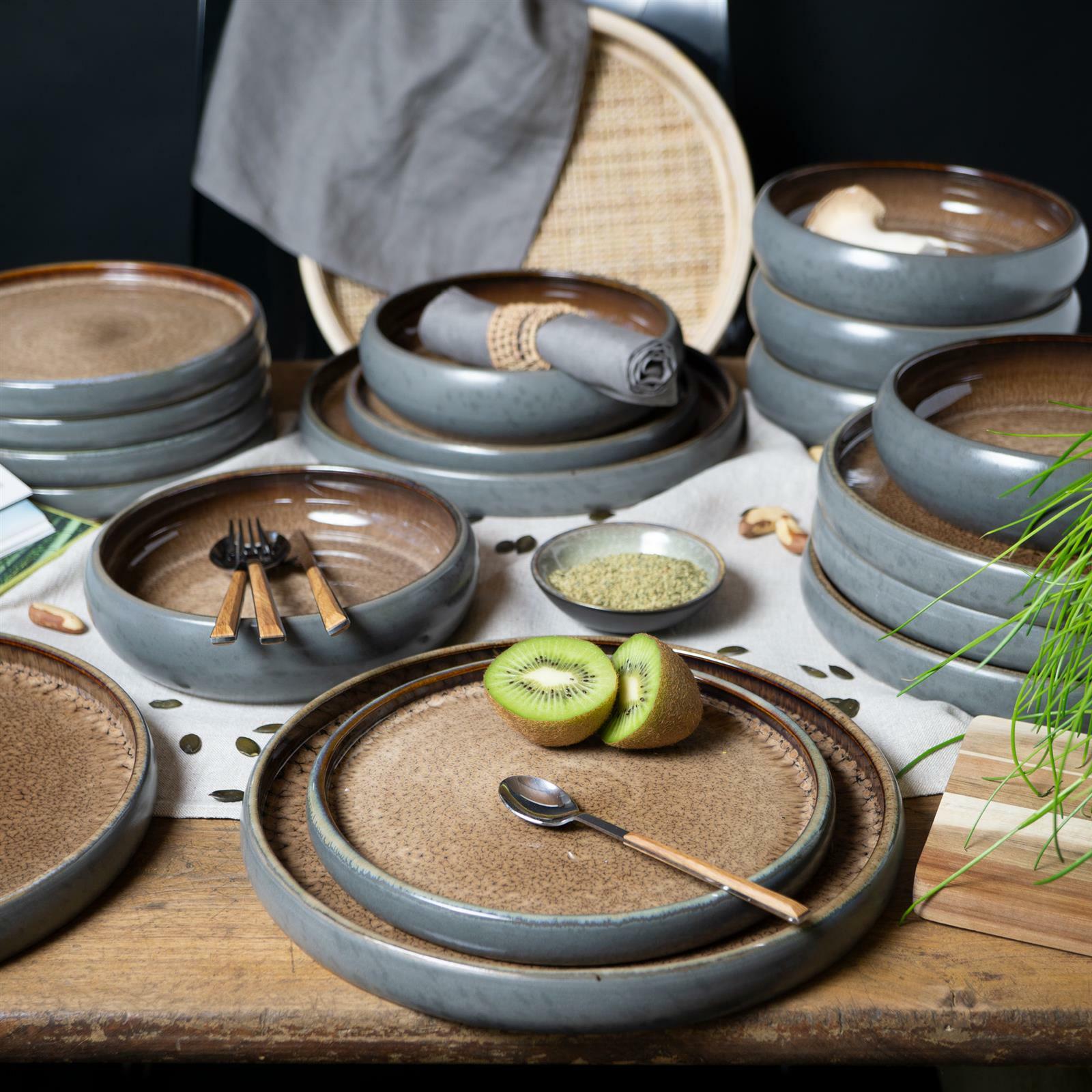 Vogelperspektive auf ein 18-teiliges Tafelservice in Beige und Grau, bestehend aus Tellern und Schalen, dekoriert mit Besteck und Kiwi.