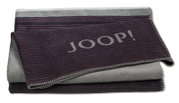 Gefaltete Decke mit lila und grauen Streifen, Markenname JOOP! sichtbar, von oben fotografiert.