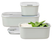 Drei Frischhaltedosen in verschiedenen Größen, gefüllt mit Reis und grünen Bohnen, aus seitlicher Perspektive.