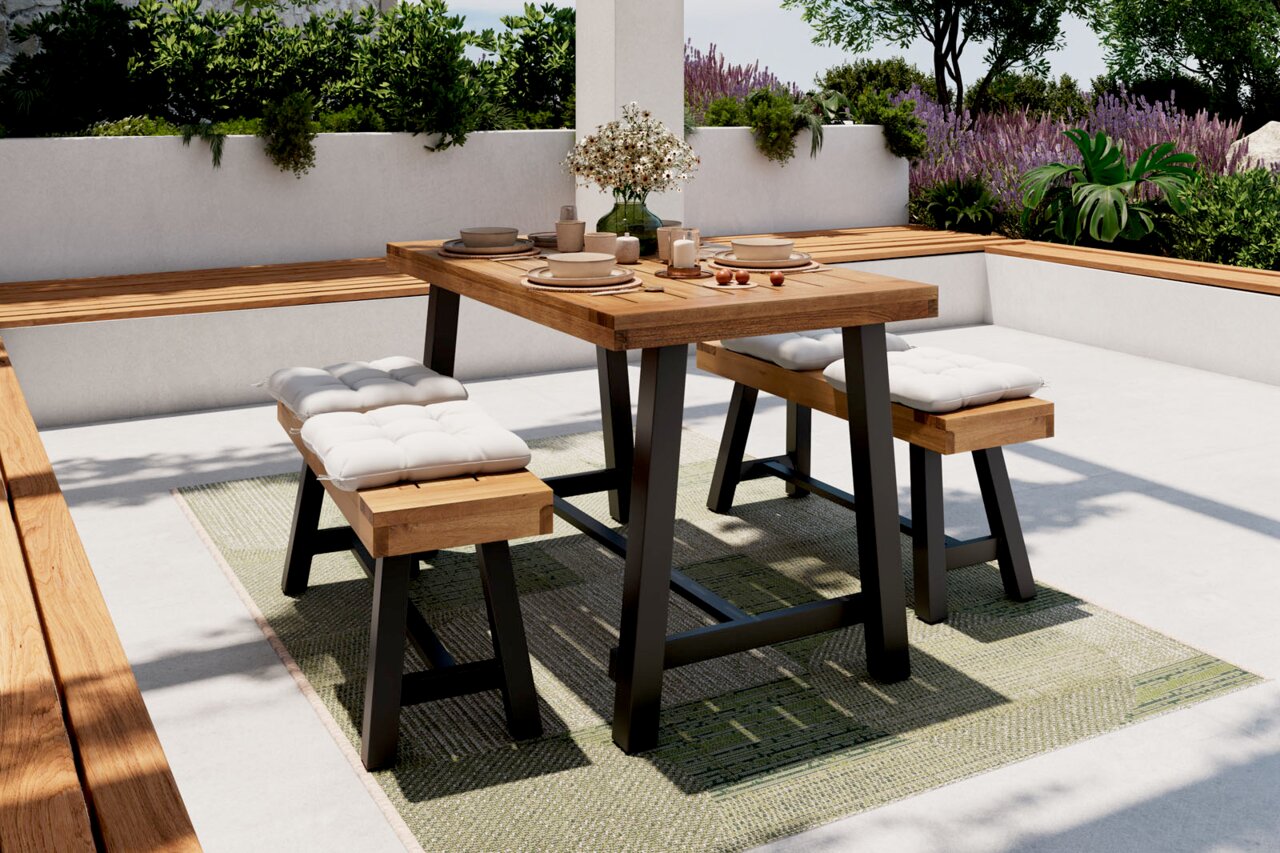 Moderner Gartentisch mit zwei Bänken, aus Holz und Metall, auf einer Terrasse mit Pflanzen im Hintergrund, aus seitlicher Perspektive.