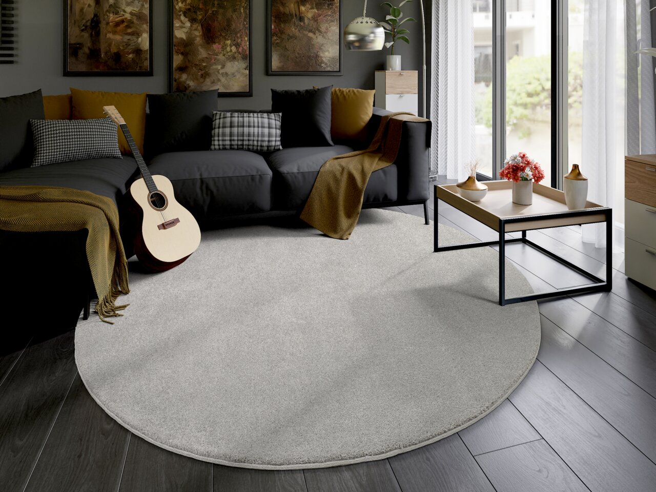 Runder, hellgrauer Uni-Teppich in einem modernen Wohnzimmer mit dunklem Sofa, Gitarre und Couchtisch. Perspektive von oben.