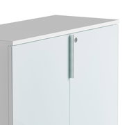 Nahaufnahme eines weißen, niedrigen Aktenschranks mit Metallgriff und Schloss, von schräg oben fotografiert.