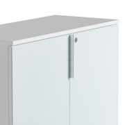 Nahaufnahme eines weißen, niedrigen Aktenschranks mit Metallgriff und Schloss, von schräg oben fotografiert.