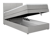 Graues Boxspringbett mit hochgeklappter Matratze und sichtbarem Stauraum, seitliche Perspektive