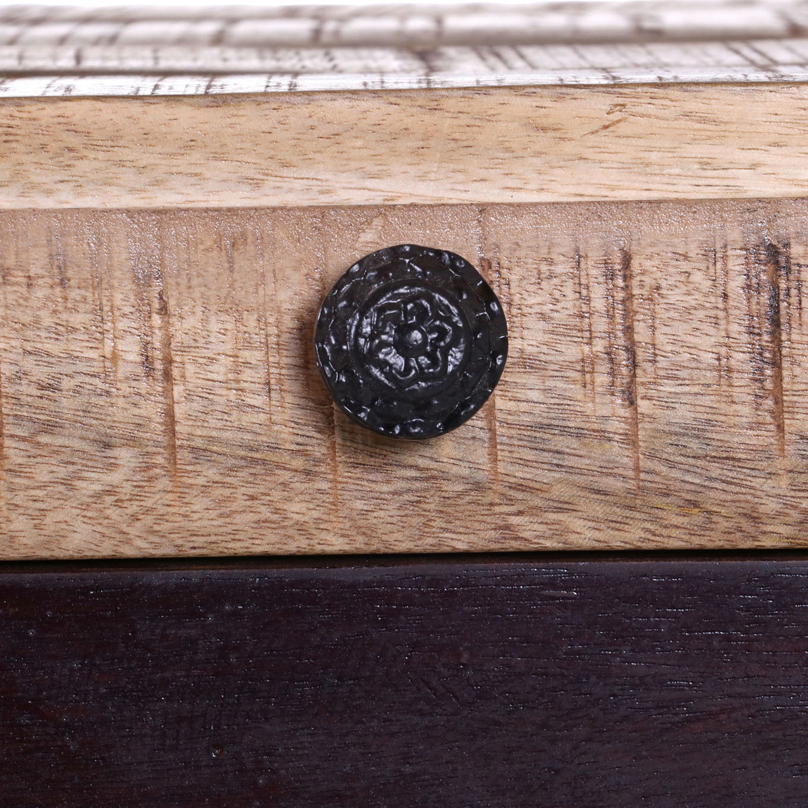 Nahaufnahme eines dekorativen schwarzen Knopfes auf einer Holzoberfläche, Teil einer Schubkastenkommode. Perspektive: Frontalansicht.