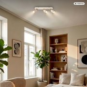 Weiße Deckenleuchte mit drei verstellbaren Spotstrahlern in einem modernen Wohnzimmer, fotografiert aus leicht schräger Untersicht nach oben zur Decke.