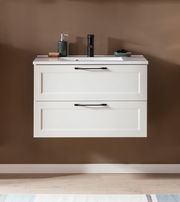 Frontale Ansicht eines modernen Waschtisch-Sets mit zwei Schubladen, weißem Finish und schwarzen Griffen, dekoriert mit Seifenspender und Accessoires.