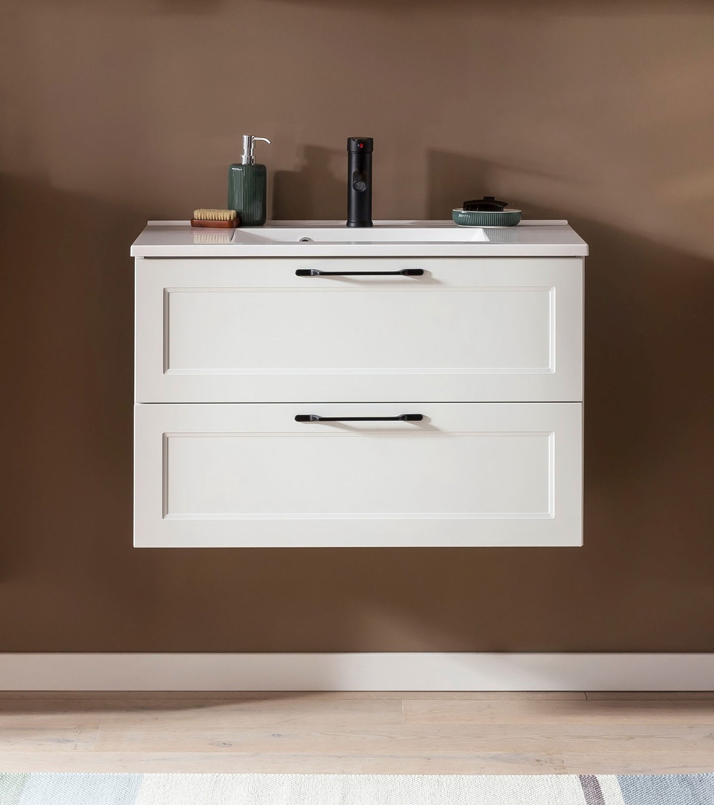 Frontale Ansicht eines modernen Waschtisch-Sets mit zwei Schubladen, weißem Finish und schwarzen Griffen, dekoriert mit Seifenspender und Accessoires.