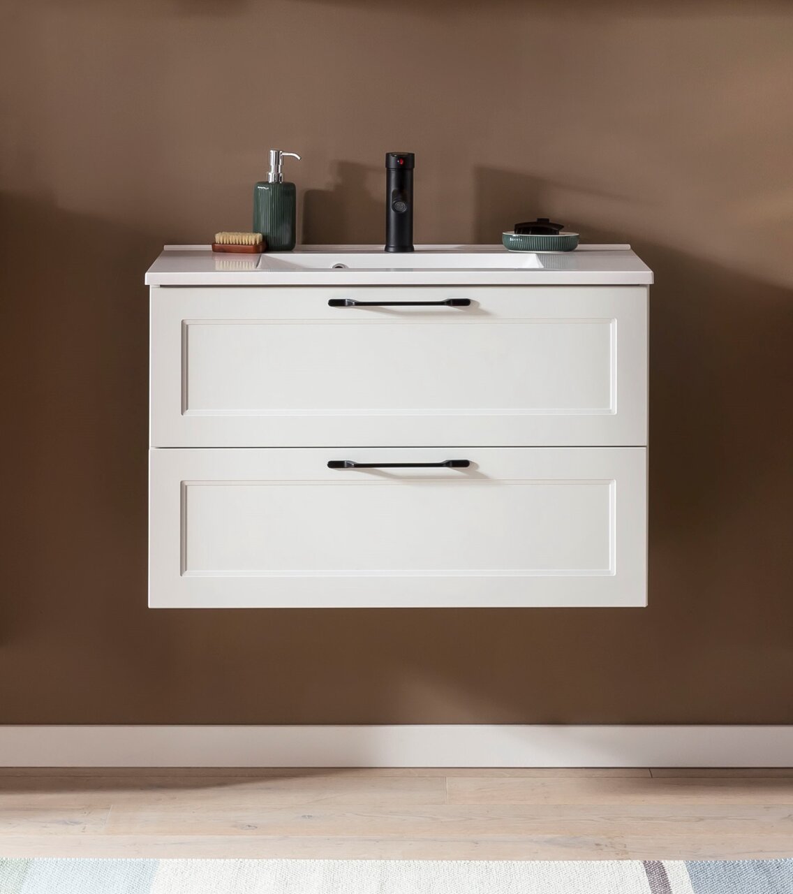 Frontale Ansicht eines modernen Waschtisch-Sets mit zwei Schubladen, weißem Finish und schwarzen Griffen, dekoriert mit Seifenspender und Accessoires.