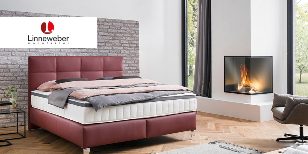 Schlafzimmer mit einem roten Polsterbett, einem Kamin und großen Fenstern. Linneweber-Logo oben.