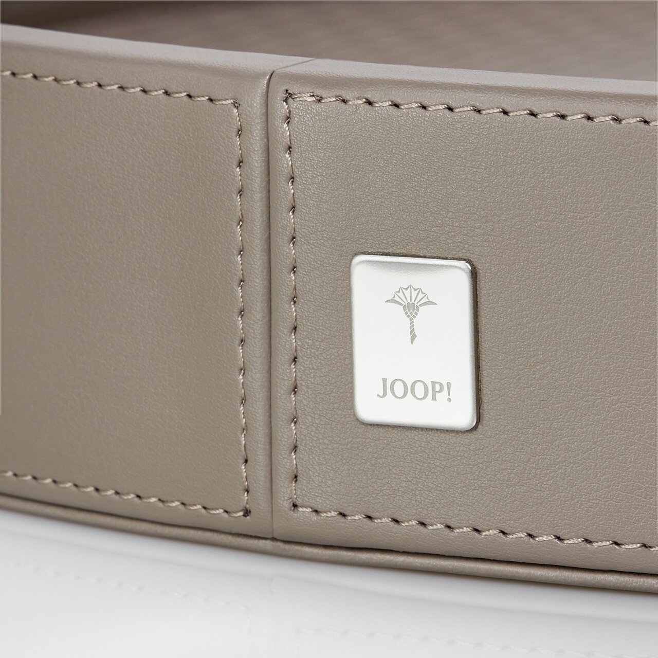 Nahaufnahme eines großen, runden, grauen Tabletts mit einem Joop!-Logo auf der Seite.