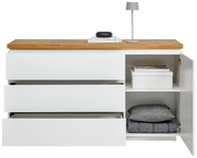 Weißes Sideboard mit drei offenen Schubladen und einem offenen Schrankfach, darauf eine Lampe und Bücher, frontale Ansicht