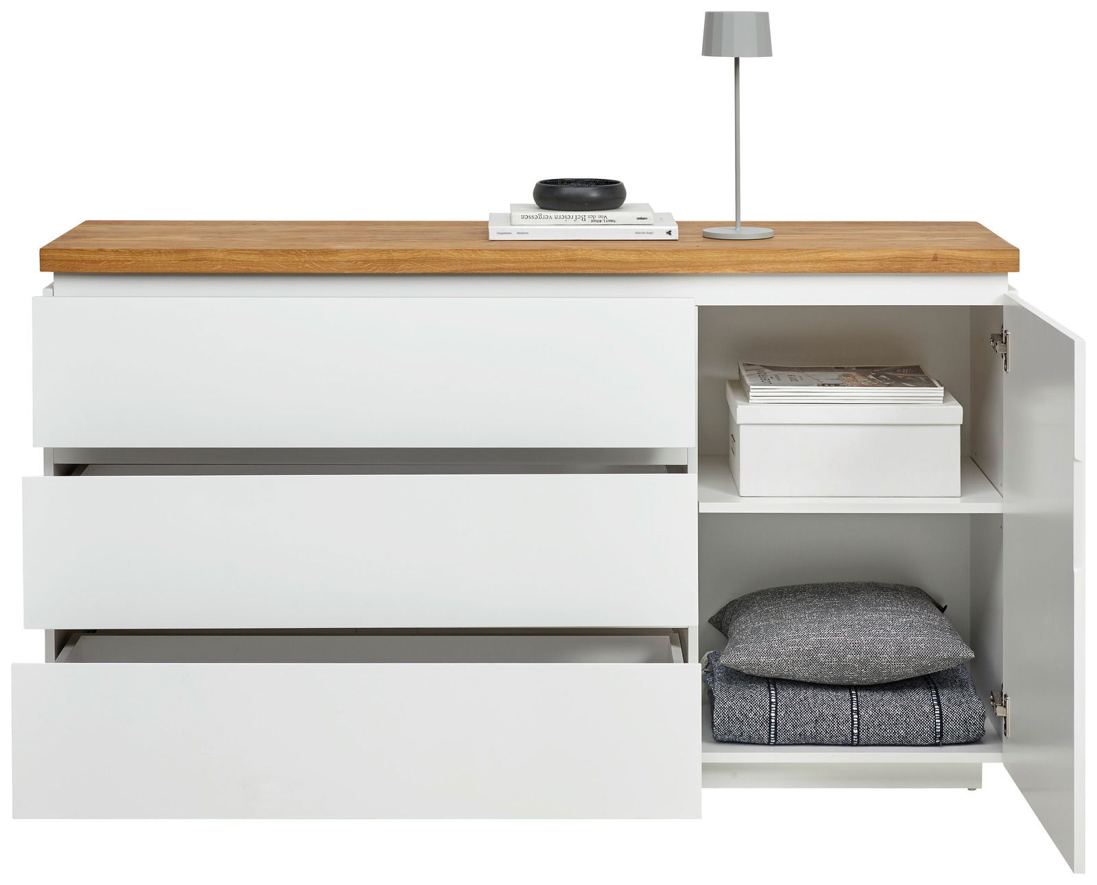 Weißes Sideboard mit drei offenen Schubladen und einem offenen Schrankfach, darauf eine Lampe und Bücher, frontale Ansicht