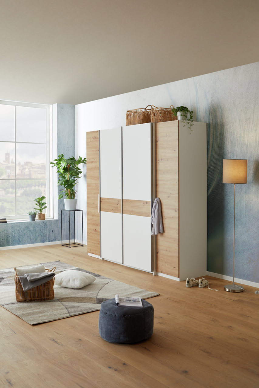 Moderner Dreh-Schwebetürenschrank mit vier Türen in Holzoptik und weißen Elementen, seitliche Perspektive im stilvoll eingerichteten Raum.