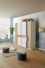 Moderne draai- en schuifdeurkast met vier deuren in houtlook en witte elementen, zijaanzicht in een stijlvol ingerichte ruimte.
