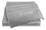 Grijze woondeken met streepmotief en groot JOOP!-logo, van voren gefotografeerd vanuit een perspectief.