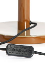 Nahaufnahme der Basis einer Tischleuchte mit braunem Standfuß und schwarzem Kabel.