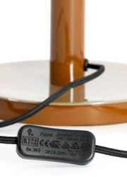 Close-up van de voet van een tafellamp met een bruine voet en een zwarte kabel.