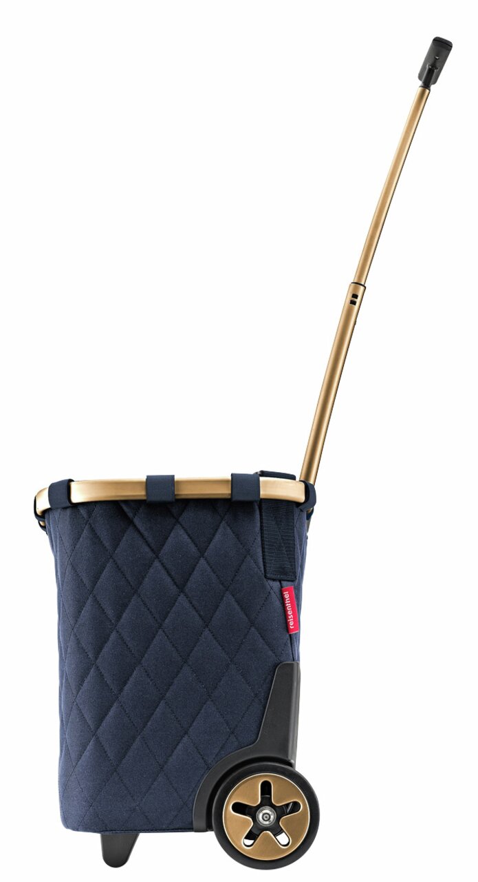 Seitenansicht eines blauen Carrycruisers mit rhombenförmigem Muster, goldfarbenem Teleskopgriff und schwarzen Rädern.