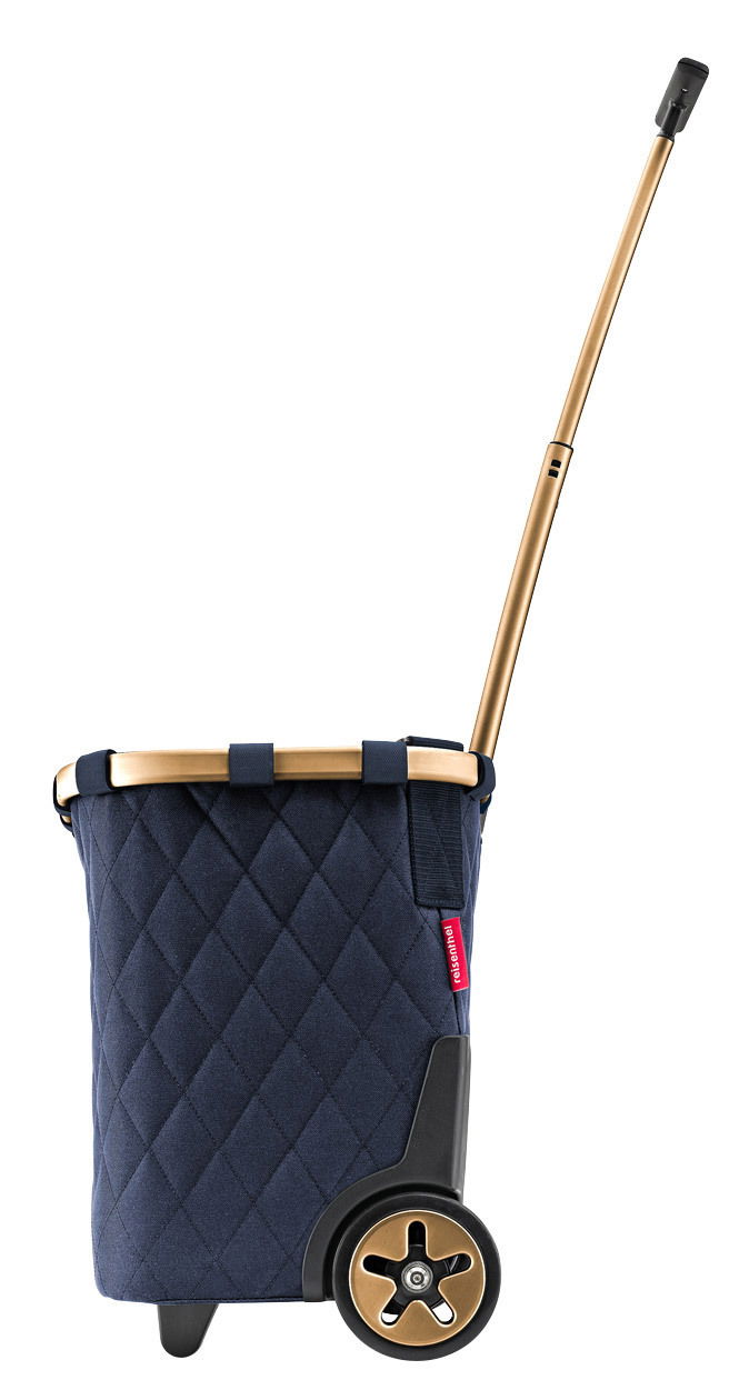 Seitenansicht eines blauen Carrycruisers mit rhombenförmigem Muster, goldfarbenem Teleskopgriff und schwarzen Rädern.