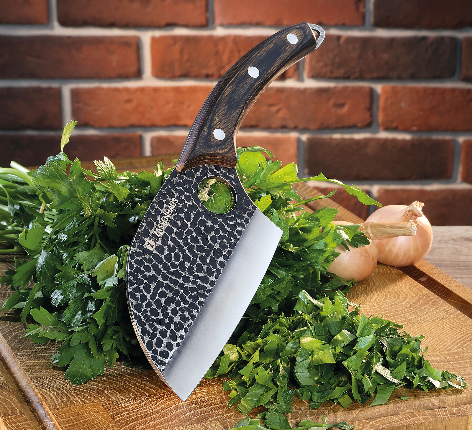 Kochmesser KEEPER 12 cm mit gehämmertem Klingenmuster und Holzgriff, auf einem Schneidebrett mit frischen Kräutern und Zwiebeln, seitliche Perspektive.