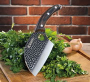 Kochmesser KEEPER 12 cm mit gehämmertem Klingenmuster und Holzgriff, auf einem Schneidebrett mit frischen Kräutern und Zwiebeln, seitliche Perspektive.