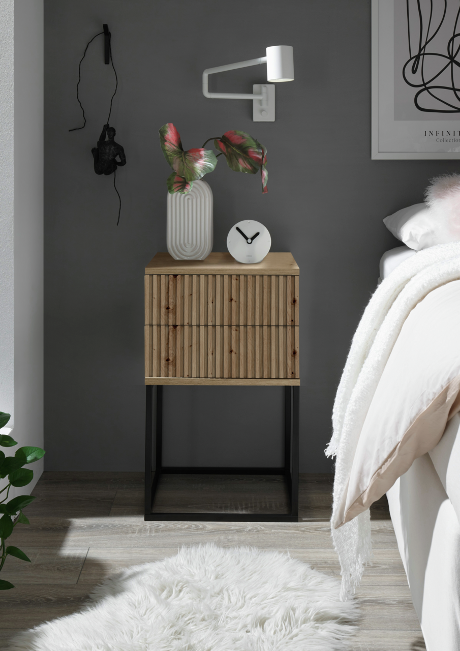 Moderne Nachtkommode aus Holz mit vertikalen Streifen, schwarzem Metallgestell, dekoriert mit einer Vase und einer Uhr, seitliche Perspektive.