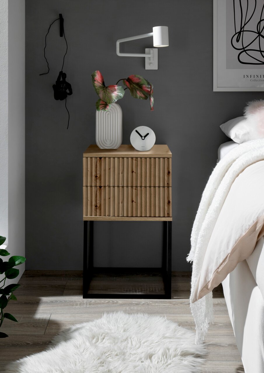 Moderne Nachtkommode aus Holz mit vertikalen Streifen, schwarzem Metallgestell, dekoriert mit einer Vase und einer Uhr, seitliche Perspektive.
