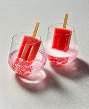 Zwei Weinbecher Forte mit rosa Getränk und roten Eis am Stiel, von oben fotografiert.