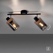 Zweiflammige Decken-Spotleuchte in Schwarz mit Holzdetails und rauchgrauen Glaszylindern, warm leuchtende E27-Leuchtmittel, fotografiert aus Untersicht von unten zur Decke.